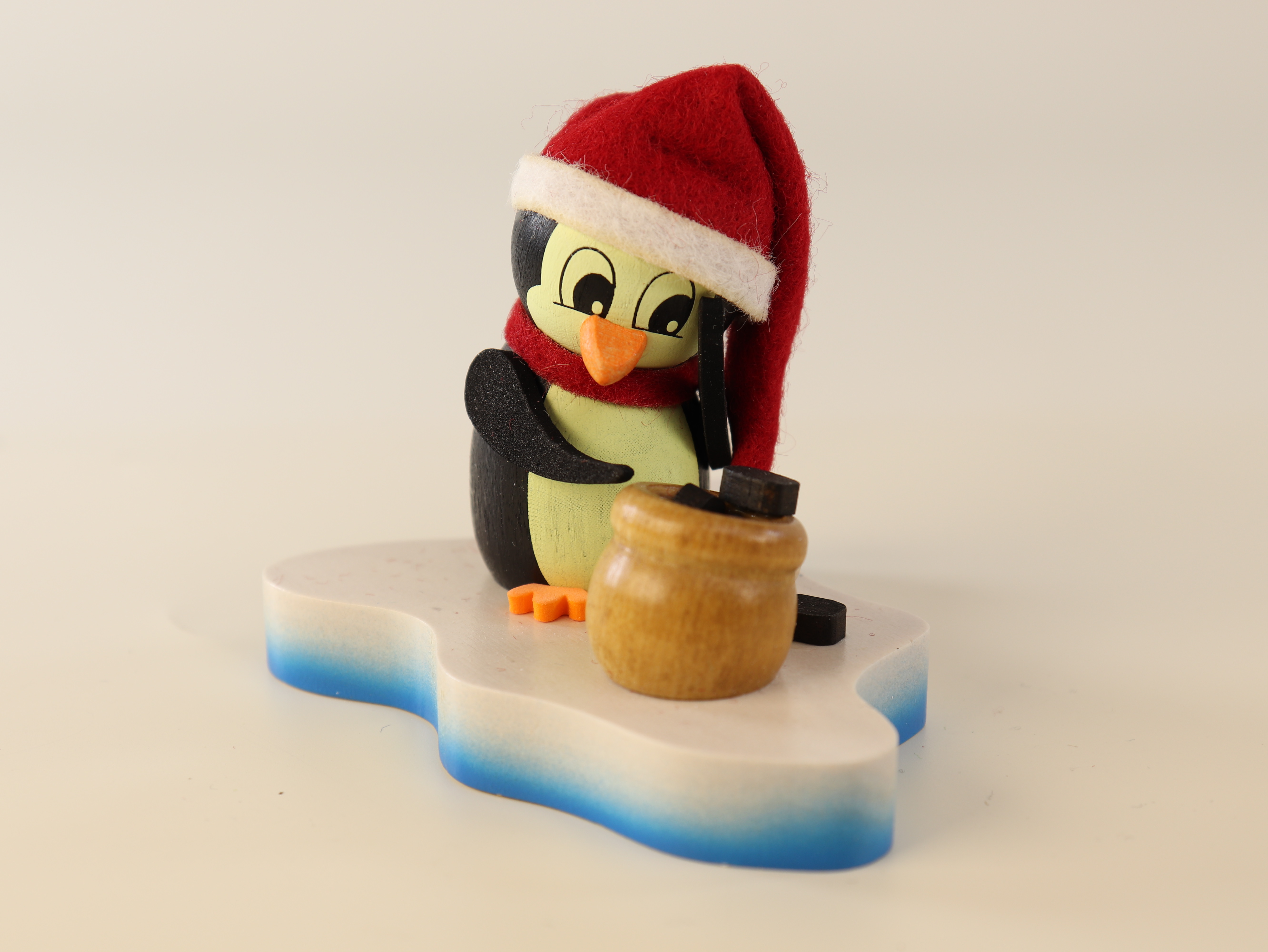 Tischdeko aus Holz 'Pinguin auf Eisscholle mit Weihnachtsmütze und Sack voll Kohle' kaufen