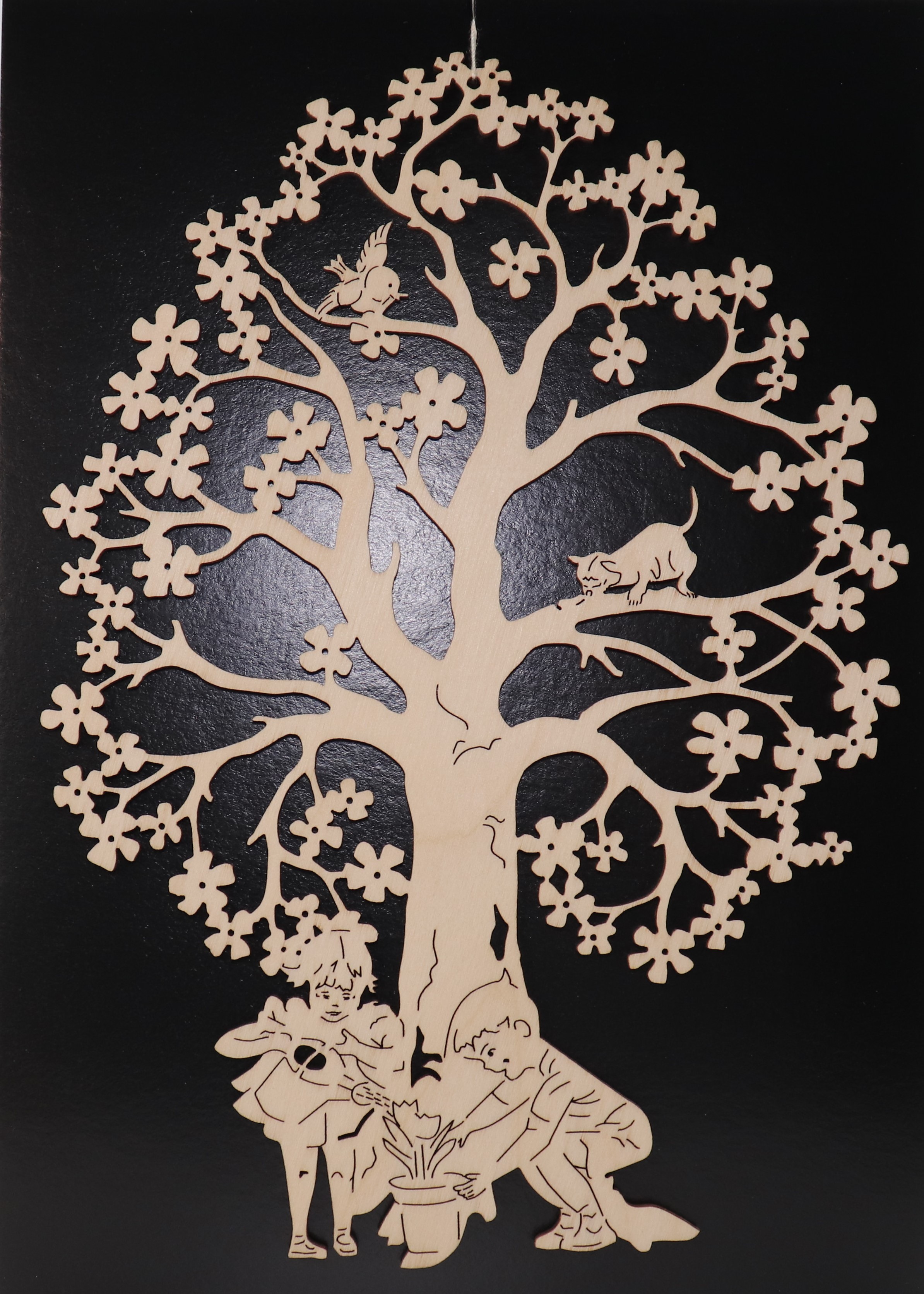 Fensterbild aus Holz mit einem Baum und zwei Kindern darunter als Motiv.