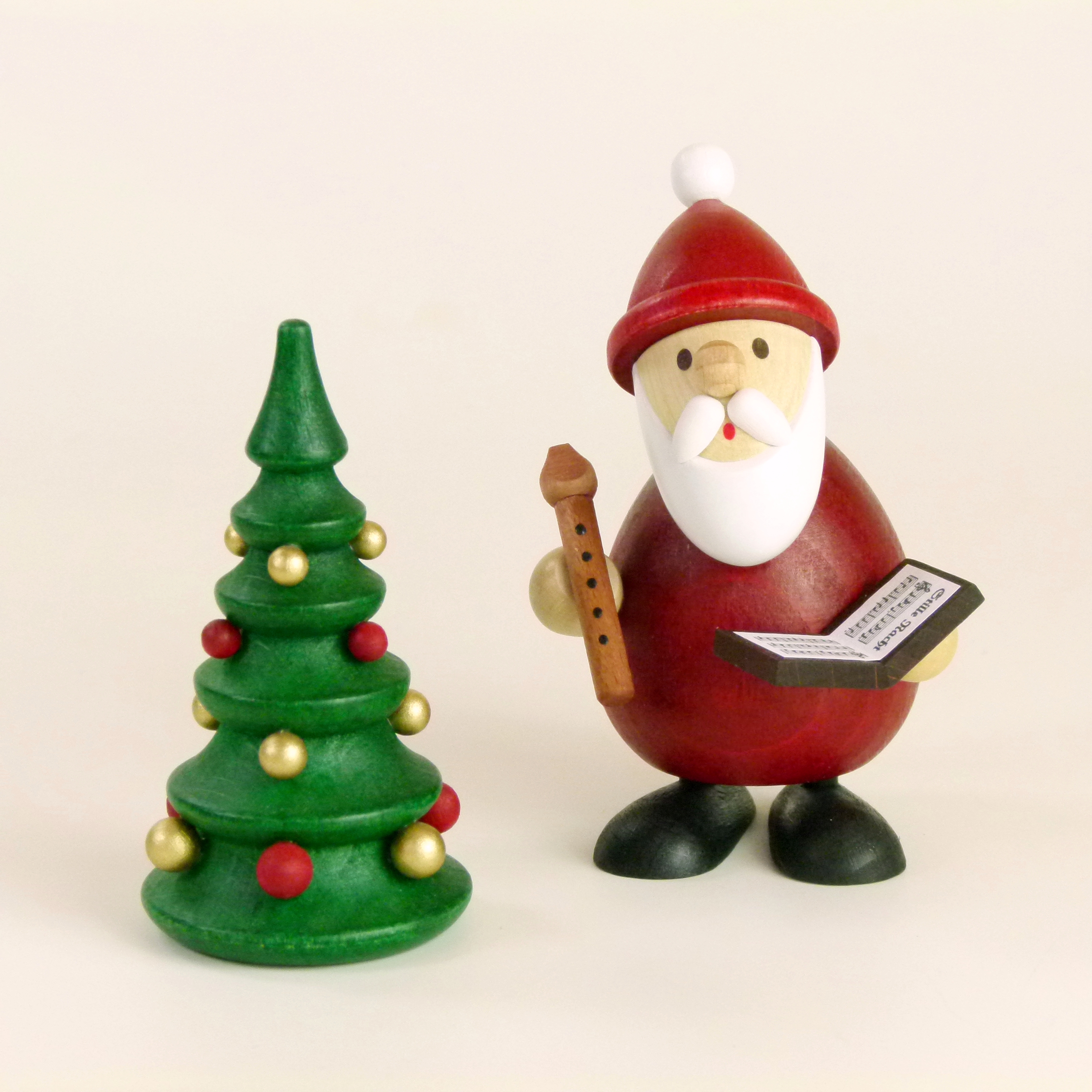 Weihnachtsmann mit Buch, Flöte und Weihnachtsbaum als weihnachtlicher Tischschmuck