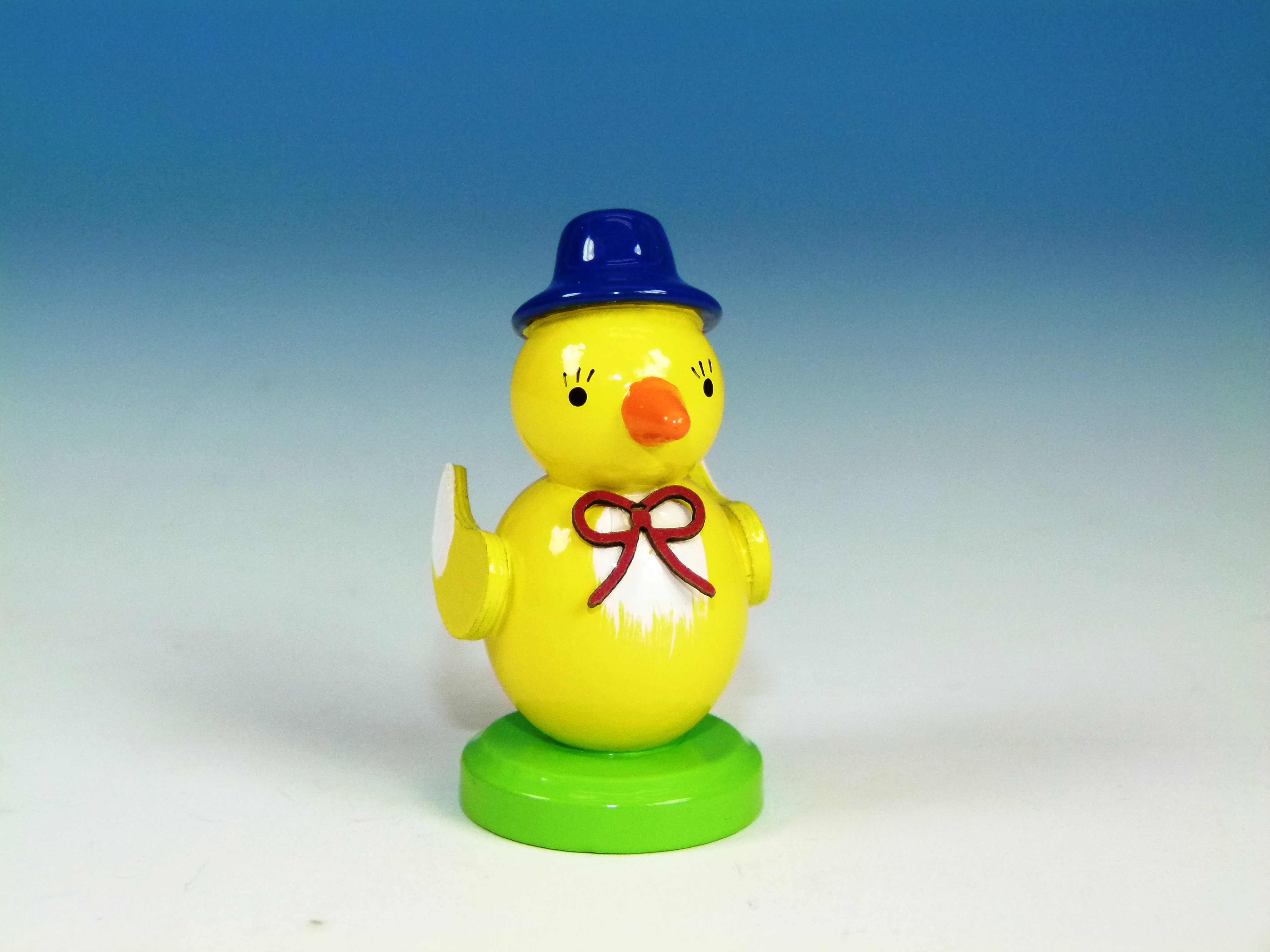 Oster-Tischdeko Küken mit blauem Hut auf grünem Sockel