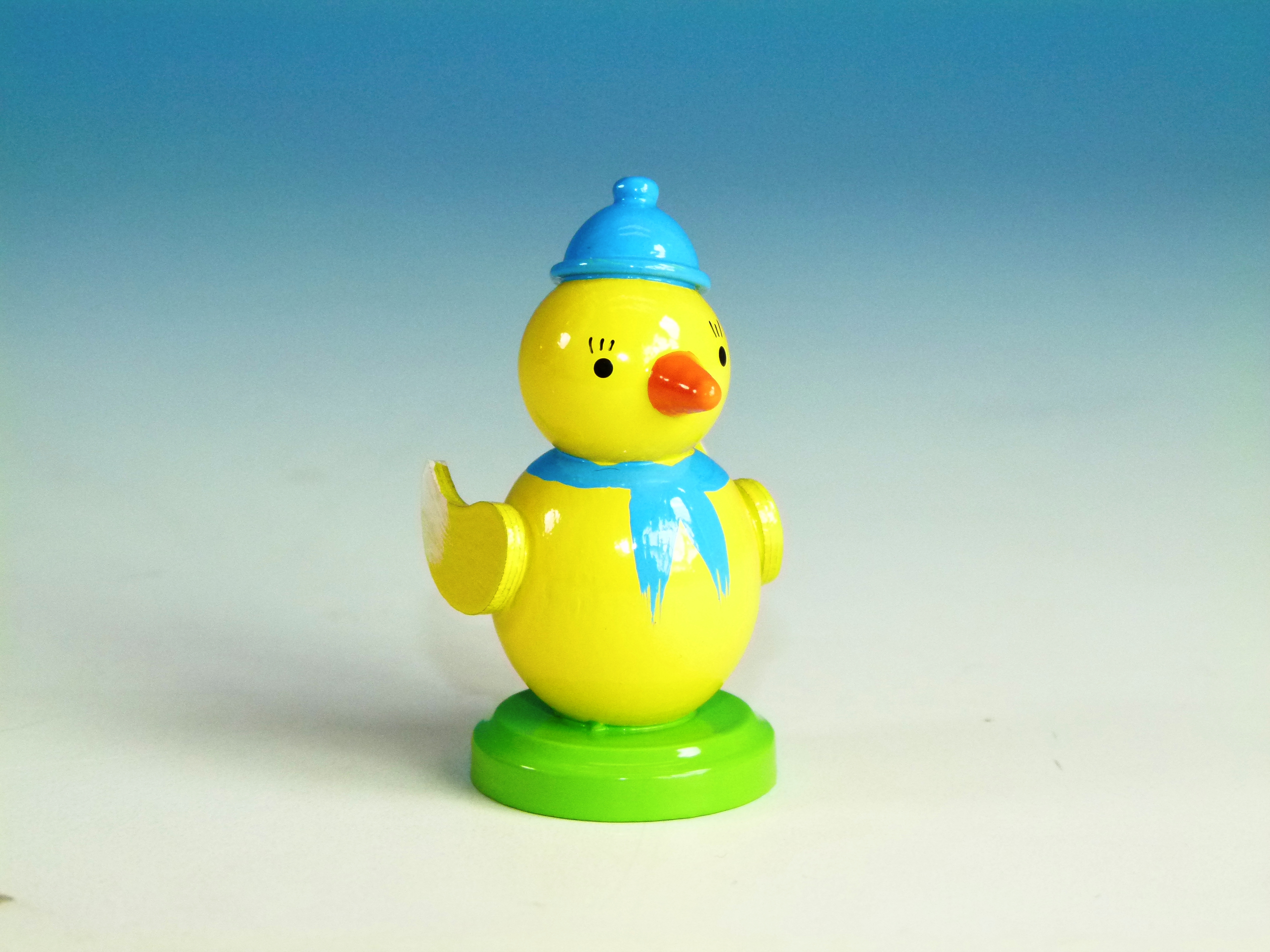 Osterdeko Küken mit blauer Mütze und Schal auf grünem Sockel