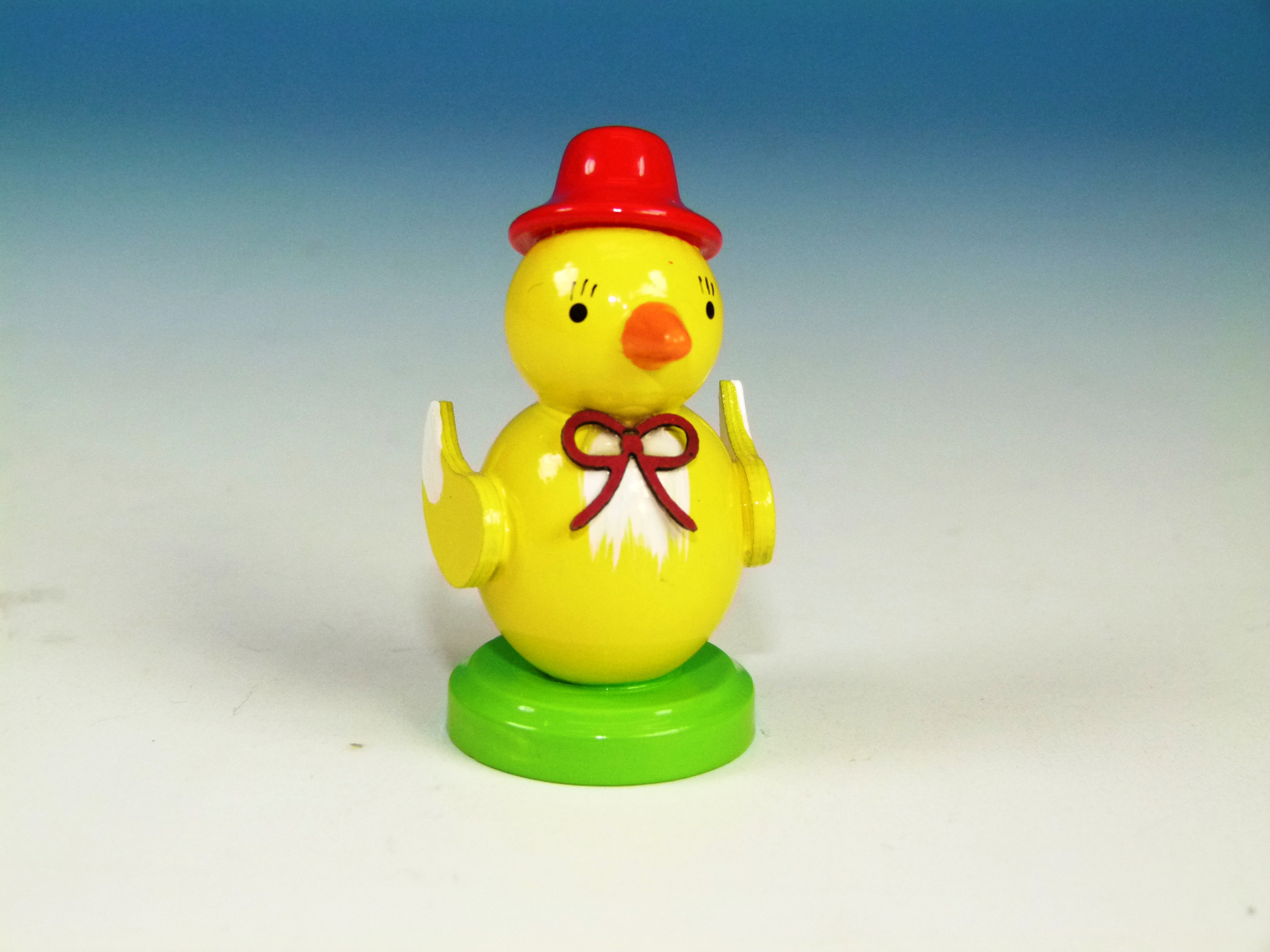 Küken mit rotem Hut und roter Schleife auf einem Sockel zum Hinstellen