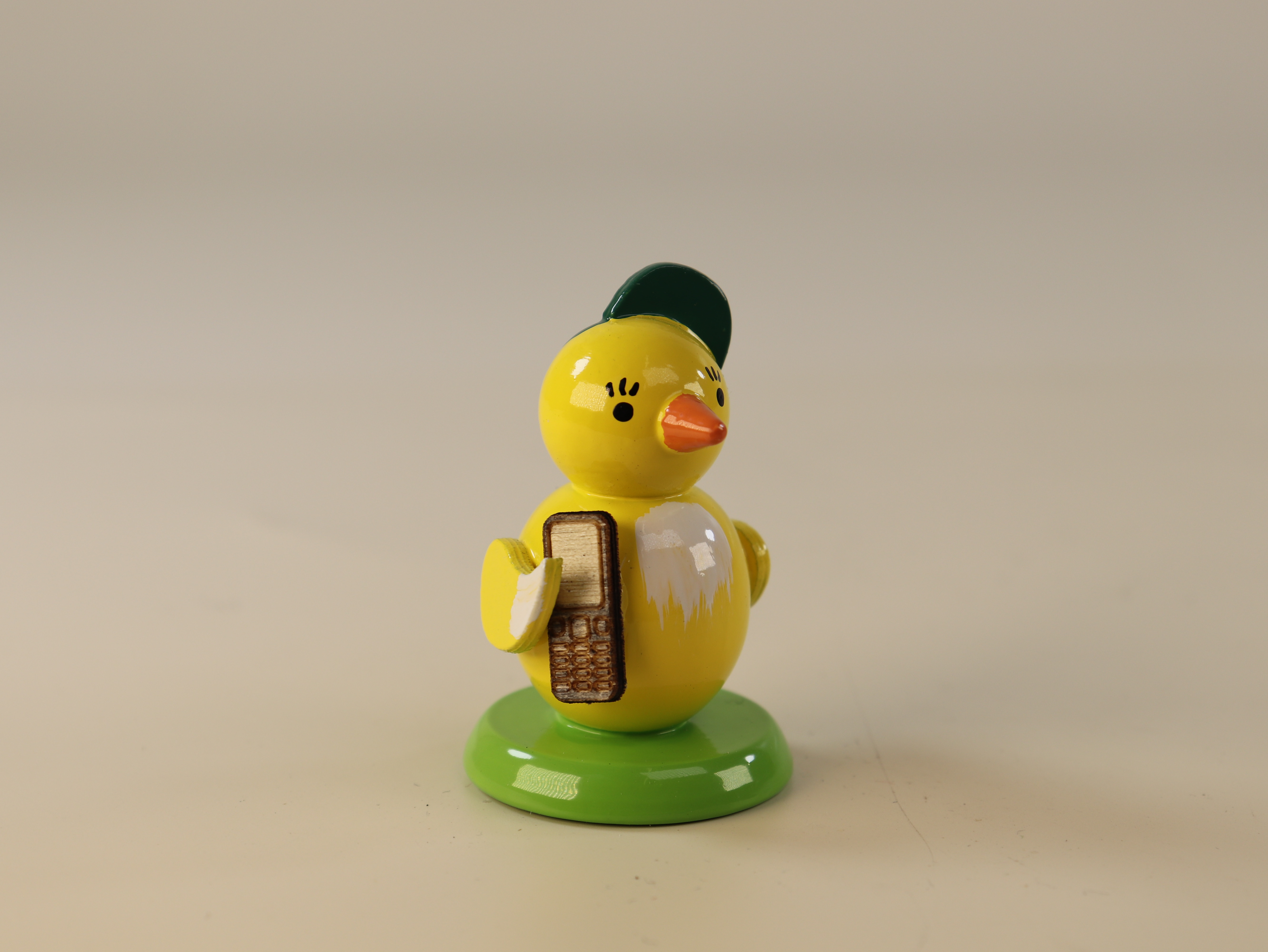 Tischdeko zu Ostern Küken mit Handy und Basecap auf grünem Sockel zum Dekorieren