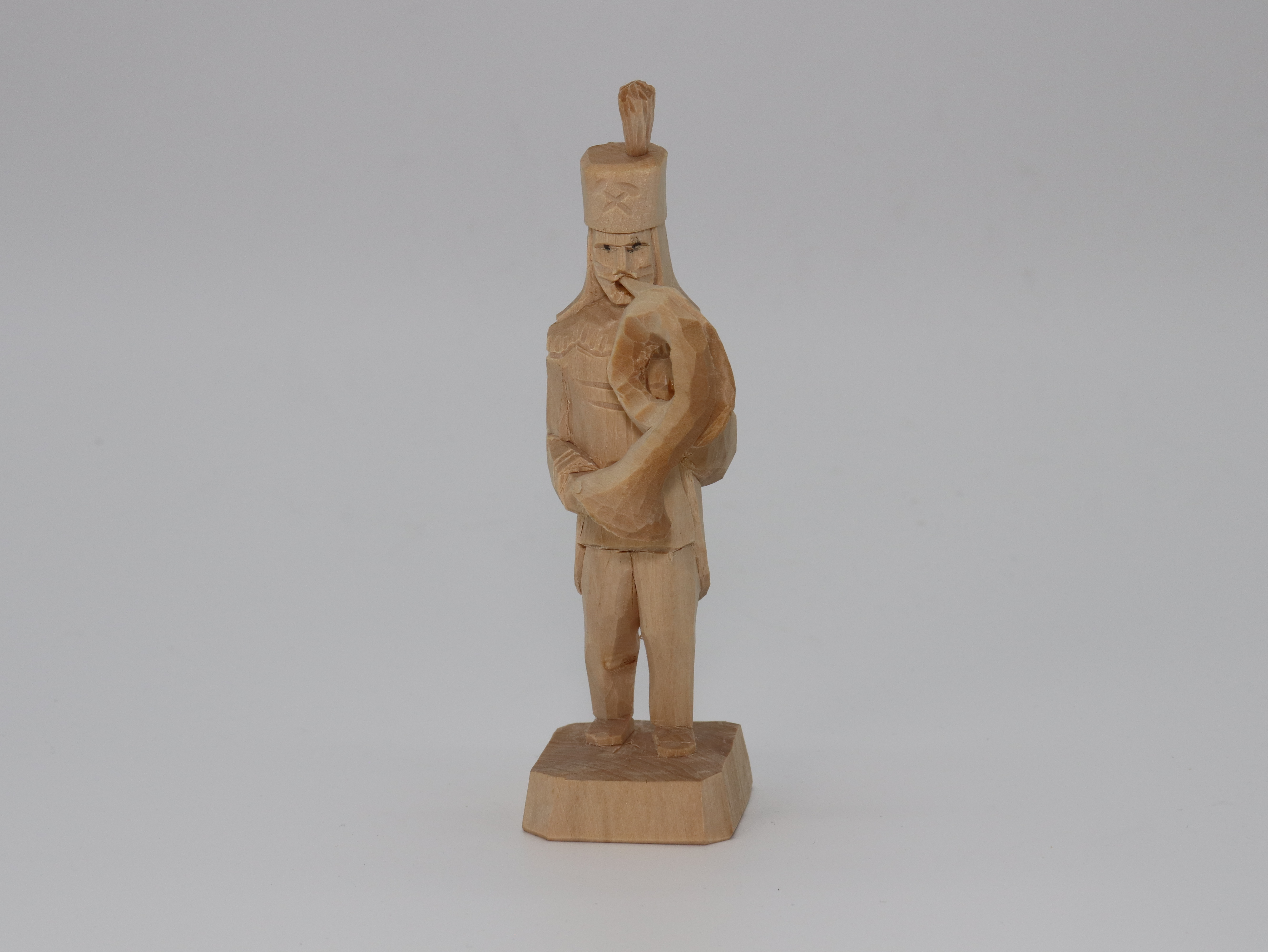 Bergmann aus Holz, naturbelassen mit Hut auf dem Kopf und Blasinstrument in der Hand.