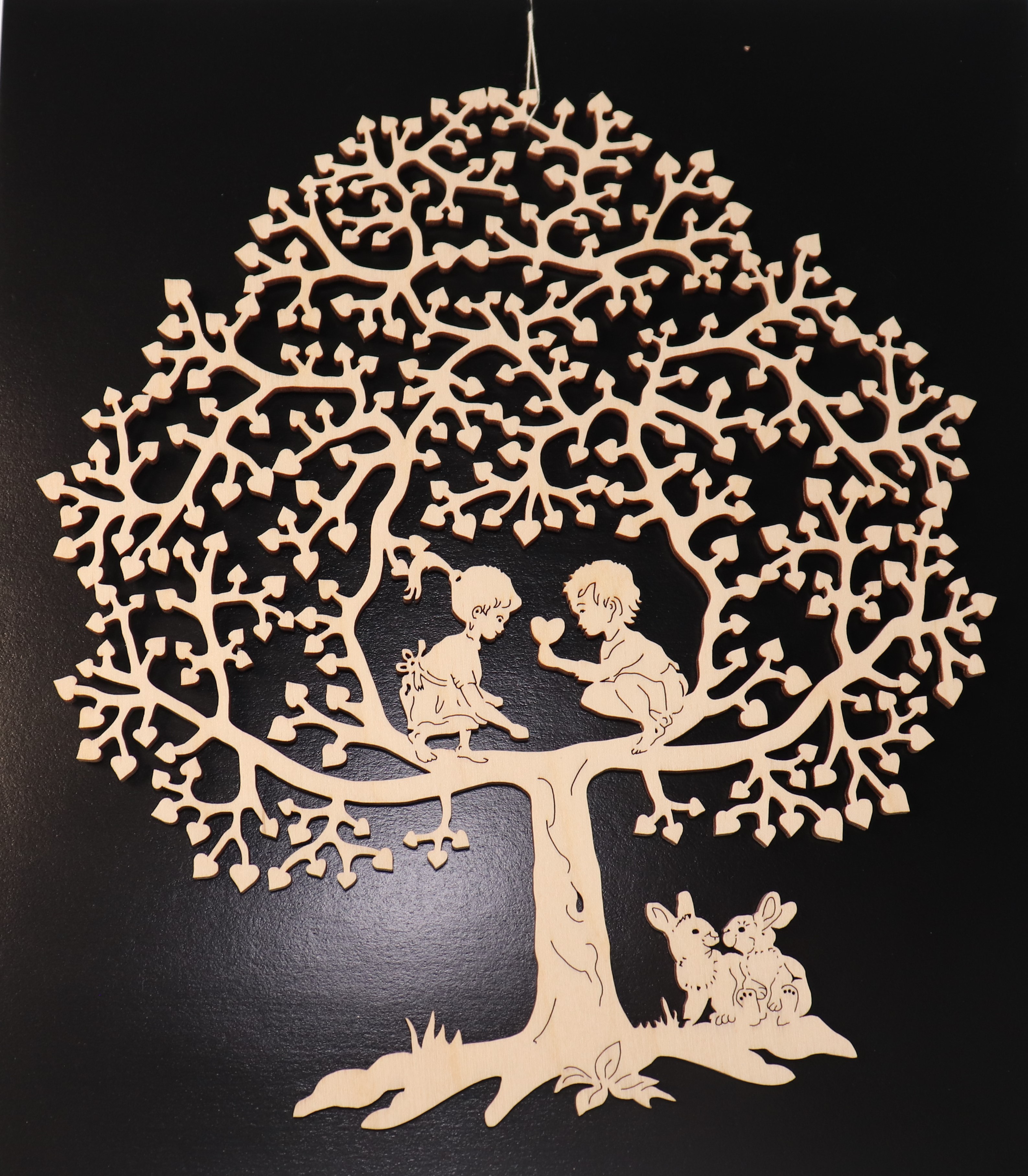 Fensterbild aus Holz mit zwei Kindern welche im Baum spielen und zwei Hasen darunter als Motiv.