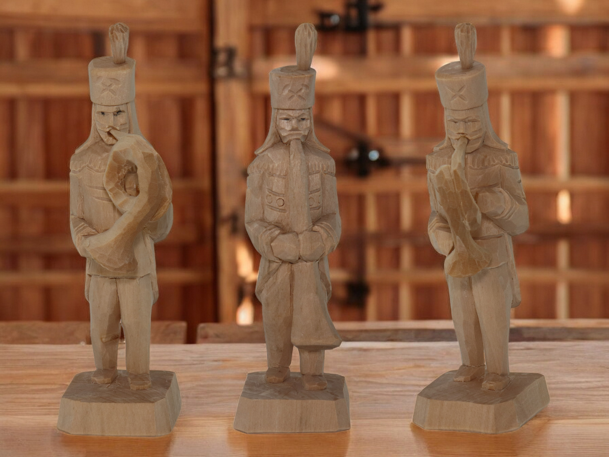 Drei geschnitzte Bergmänner aus Holz, stehend und mit Blasinstrumenten in der Hand.